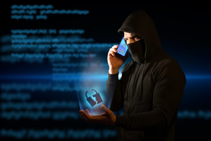 Scammer telephoning his victims while holding a broken padlock in his hand symbolizing breached security. Concept of vishing